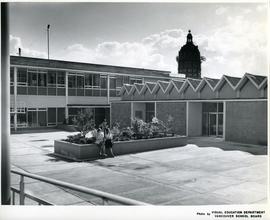 [Two students sit in a courtyard outside the Hamilton campus]